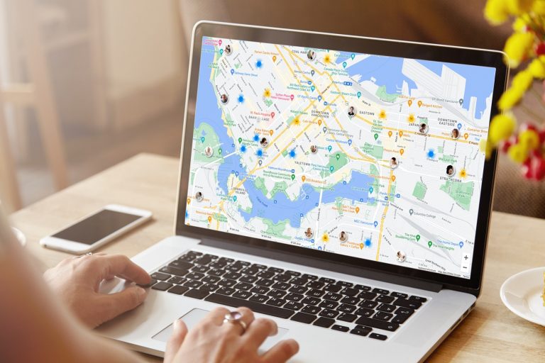 Rear view of high school girl using laptop for doing homework, browsing Internet, searching for required information, sitting at desk with mobile phone with copy space screen lying next to her